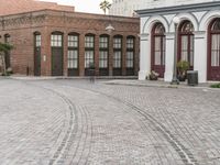 a brick road with old windows and buildings in the background and an empty area on the ground