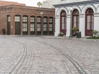 a brick road with old windows and buildings in the background and an empty area on the ground