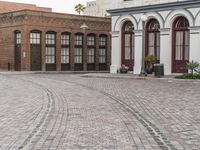 a brick road with old windows and buildings in the background and an empty area on the ground