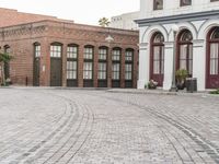 a brick road with old windows and buildings in the background and an empty area on the ground