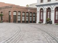 a brick road with old windows and buildings in the background and an empty area on the ground