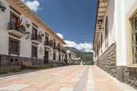 a long brick street with a line of buildings with arches in them and a sidewalk with tiles in front