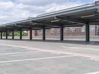 a parking lot in an industrial area with several parking bays under the roof and some buildings in the background