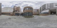 a fisheye photo of the building in the background and surrounding architecture behind it are two circular buildings, one is a library and the other is a museum