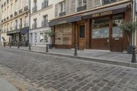 an empty street in front of a cafe with lots of windows and wooden doors on it