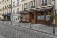 an empty street in front of a cafe with lots of windows and wooden doors on it