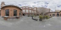 a view from the camera looking at buildings and a sky background behind it in the middle of a wide panoramic photo