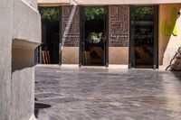 people walk in the empty streets near small tables and umbrellas and a building with balconies on the windows