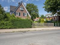 a house sits next to a fence on the street corner of a residential area with trees