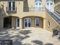 a home with patio, staircases and railings in the back yard area of a house