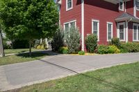 a large brick house with white windows next to a sidewalk and green trees on either side of the street