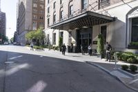 three people in suits standing outside the entrance to a large hotel or apartment building with an awning