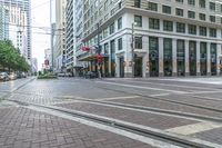 there is a pedestrian in the street next to the building and tracks with no cars