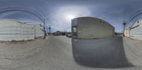 a round image of a street next to an industrial building and an old car on the road