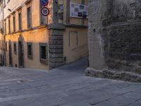 an alley with cobblestone pavement and stone building, and street signs for no walking