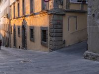 an alley with cobblestone pavement and stone building, and street signs for no walking