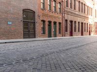 red bricked brick building near green door and street scene on the edge of a brick road