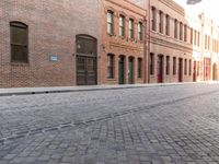 red bricked brick building near green door and street scene on the edge of a brick road