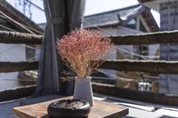 there is a table and chairs on this porch, and with a glass vase with pink flowers