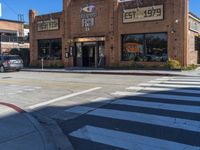 an empty road by an old building with storefront signs in windows and an intersection in front of the store