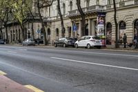 this is a street that is full of cars, bicycles and pedestrians on it and people walking by