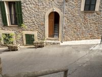 the building is made of stones and stone walls and two chairs and one potted planter