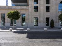 a building with two large round marble planters on the sidewalk next to a tree