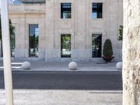 a building with two large round marble planters on the sidewalk next to a tree