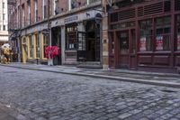 a building that has two red umbrellas on it and a brick road in front of them