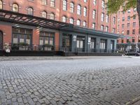 a parking meter is pictured on a brick street in front of the hotel and apartment building