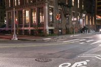 a crosswalk at night near a busy city street with buildings and a no parking sign