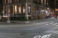 a crosswalk at night near a busy city street with buildings and a no parking sign