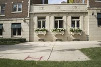 a white building with flowers and plants on it's side walk next to a sidewalk