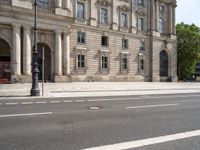 an empty street with a building and traffic light near by it on a sunny day