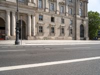 an empty street with a building and traffic light near by it on a sunny day