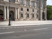 an empty street with a building and traffic light near by it on a sunny day