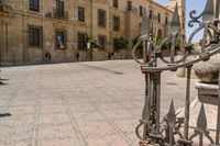 a man walks down a paved street past stone buildings and orange trees that sit on either side