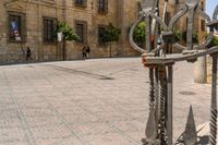 a man walks down a paved street past stone buildings and orange trees that sit on either side