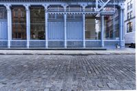 a red fire hydrant stands near the edge of a brick street in front of a blue building
