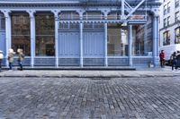 a red fire hydrant stands near the edge of a brick street in front of a blue building
