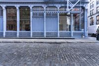 a red fire hydrant stands near the edge of a brick street in front of a blue building