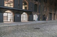 a cobblestone street and a building that is closed off from the light with windows