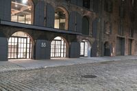 a cobblestone street and a building that is closed off from the light with windows