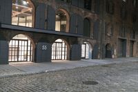a cobblestone street and a building that is closed off from the light with windows