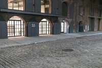 a cobblestone street and a building that is closed off from the light with windows
