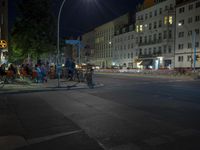 man on bike waiting to cross the road at night in urban area with buildings in the background