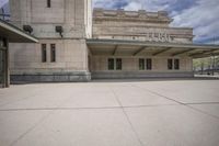 a large building with a sidewalk in front of it and a parking sign that says,