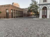 a red brick street that has two building on one side and one in the other