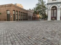 a red brick street that has two building on one side and one in the other