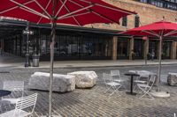 tables and umbrellas outside on brick sidewalk with buildings in background and cobblestone